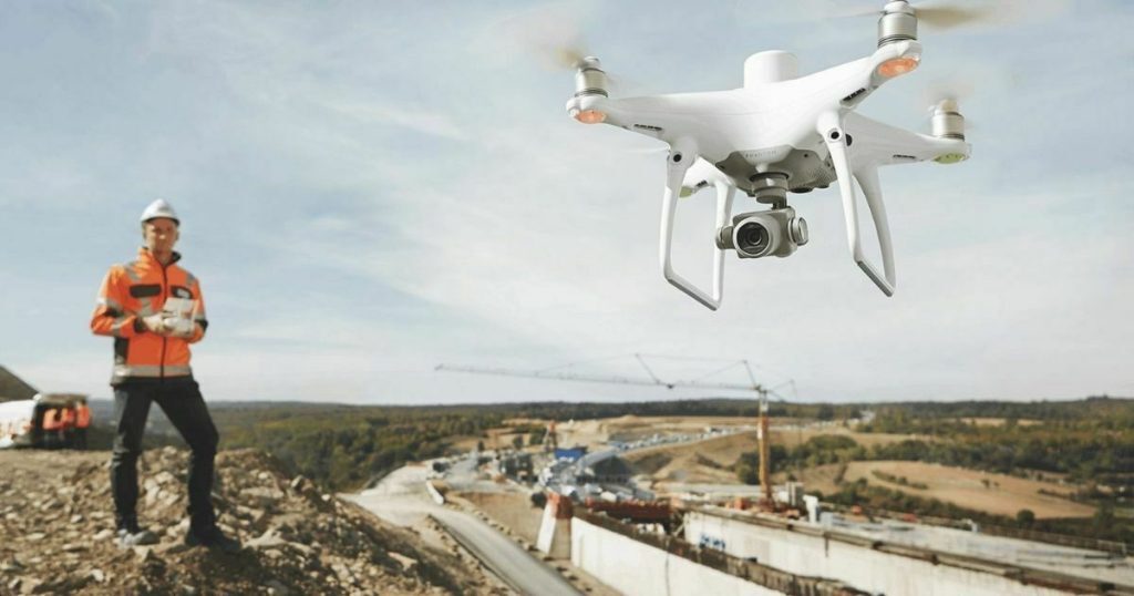 Drone terbang di atas area yang sedang dipetakan, menunjukkan penggunaan teknologi UAV untuk pemetaan
